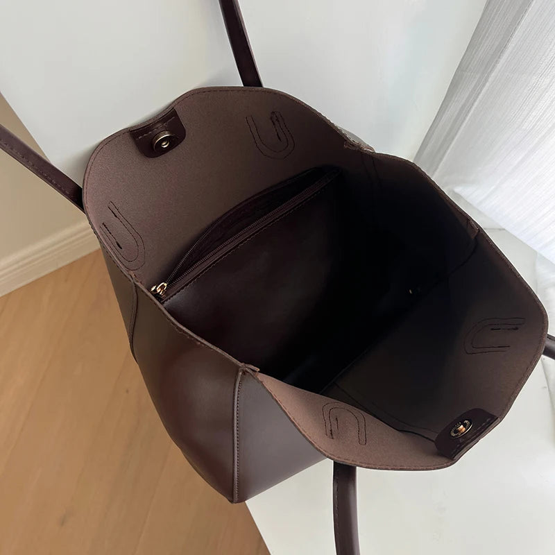 A dark brown vintage large-capacity tote bag hanging on a hook against a white wall.