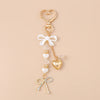 Gold pearl bow heart keychain with a dangling charm