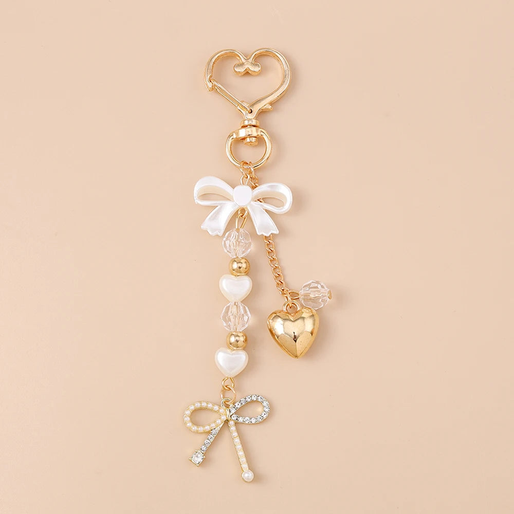 Gold pearl bow heart keychain with a dangling charm