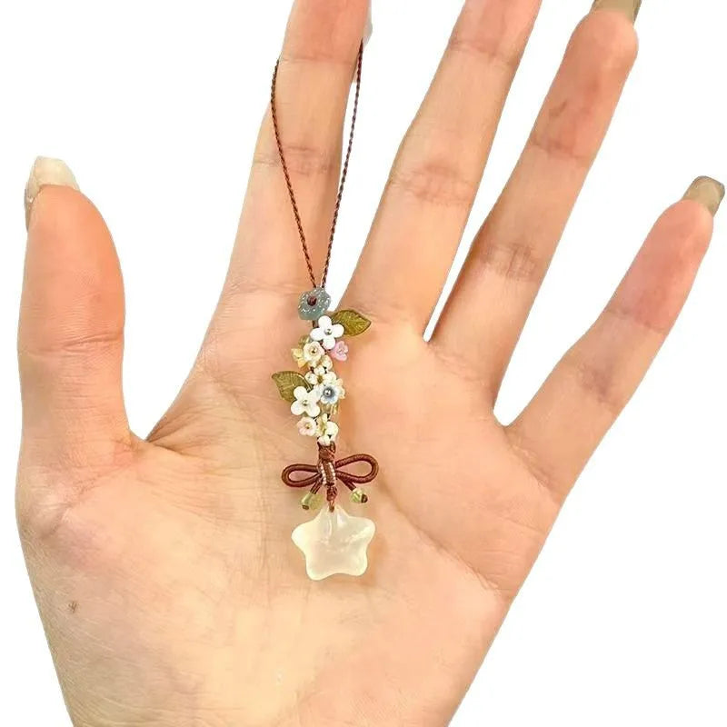 Une main tient un pendentif de fleur étoile transparente en glace avec un cordon brun délicat.