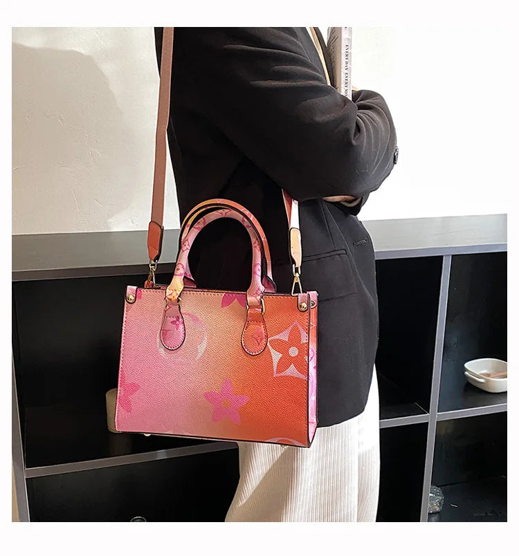 A pink and orange patterned ladies' shoulder tote bag carried by a person in a black blazer.