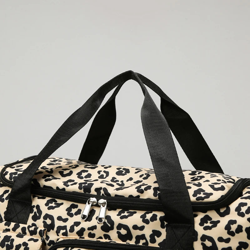 A close-up view of a leopard print travel duffel bag with black straps and a zipper detail.