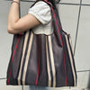 A person carrying a brown and beige striped foldable oxford grocery tote bag.