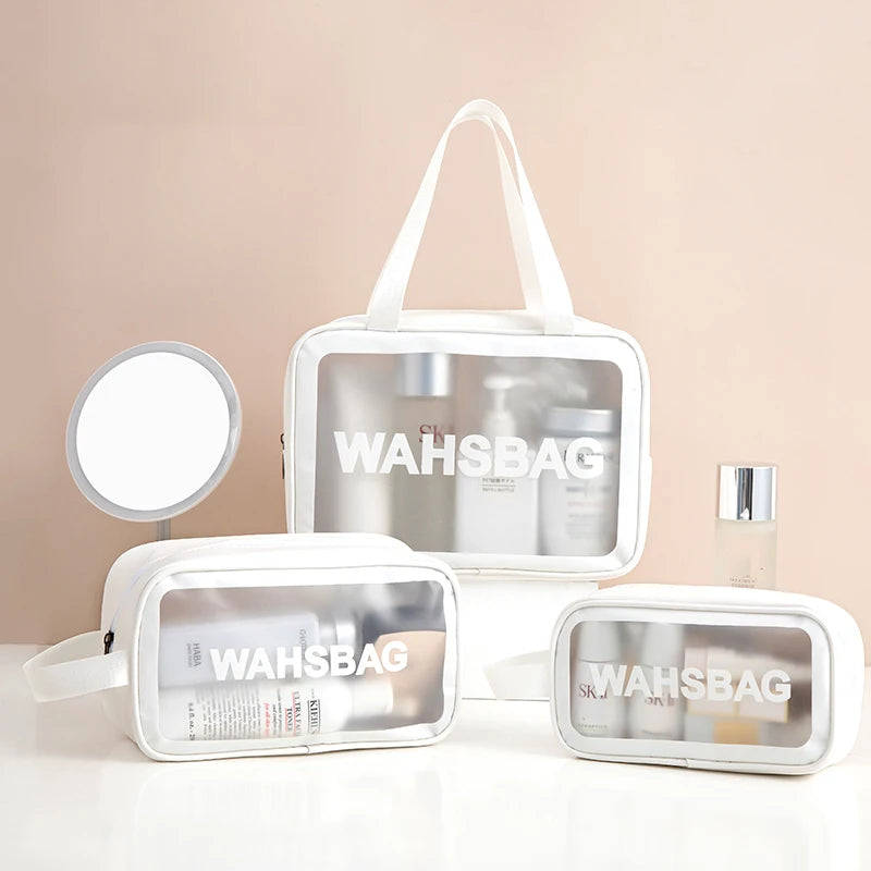 A clear waterproof travel toiletry bag with a white strap and multiple compartments is displayed on a white surface.