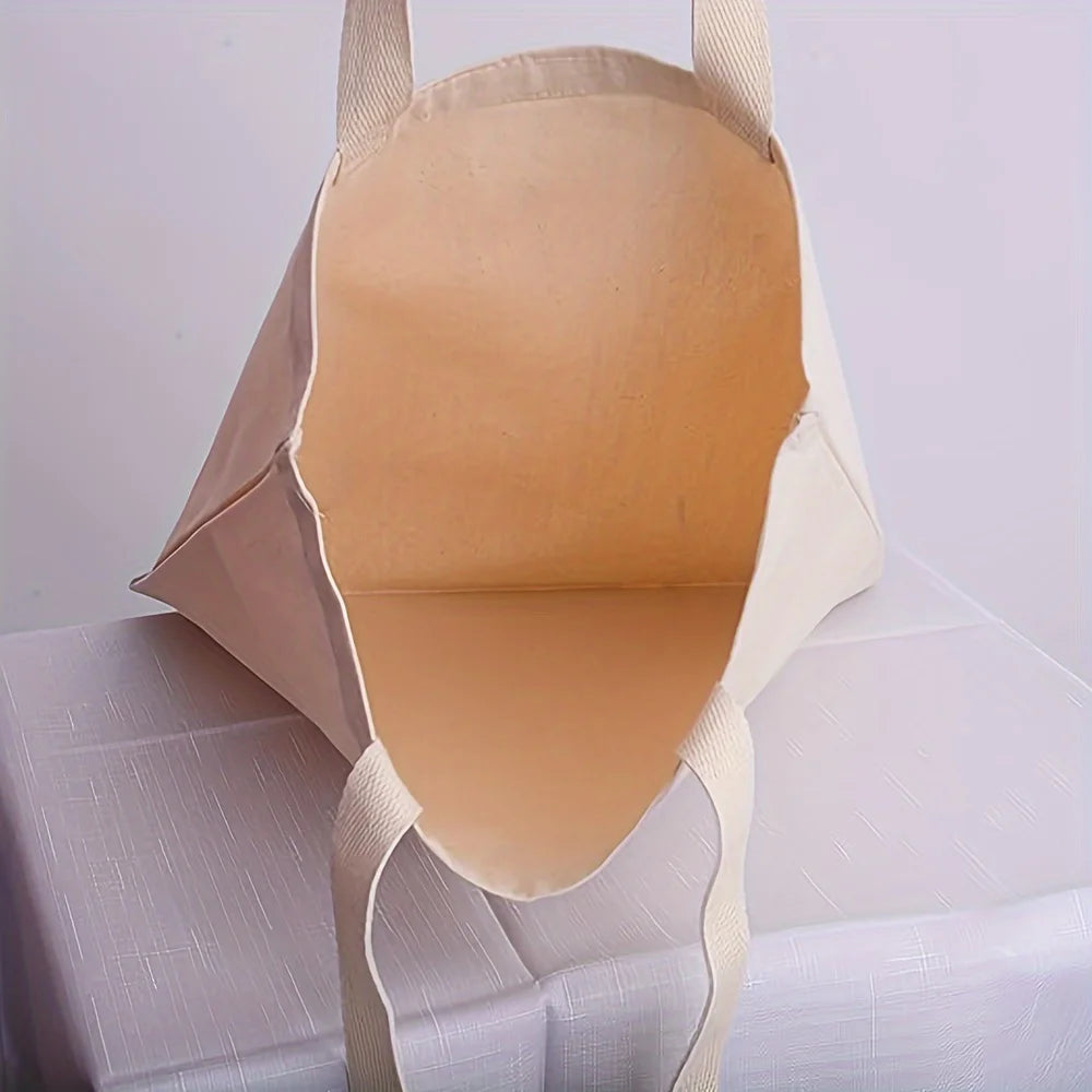 Un sac en toile de coton beige clair est montré ouvert, affichant son intérieur et sa texture de tissu.