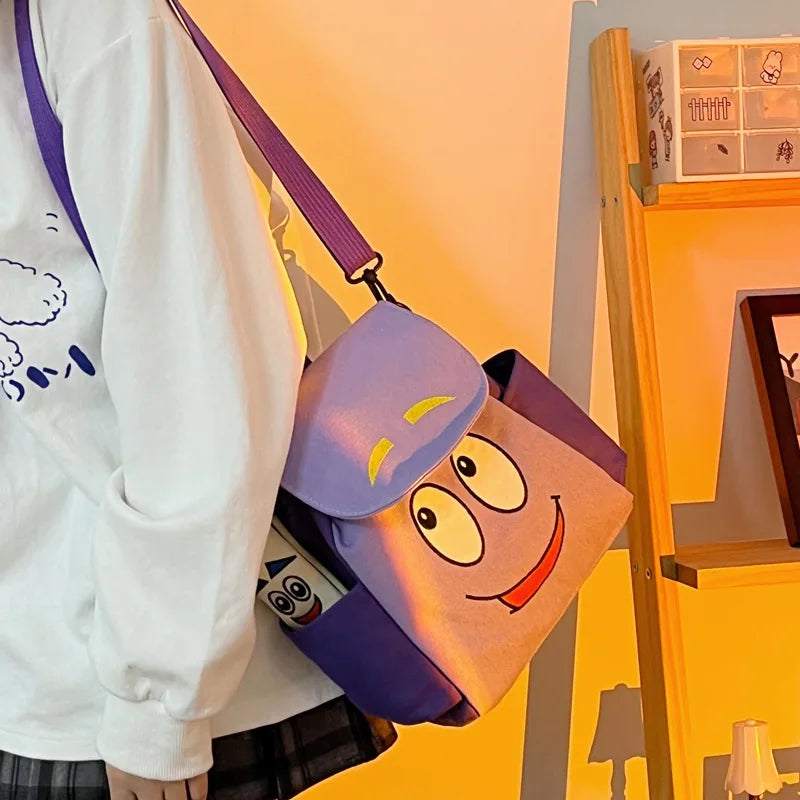A purple and yellow Dora The Explorer cartoon flannel backpack is displayed on a wooden shelf.