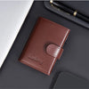 A brown leather card holder with a pop-up slide is shown on a dark surface next to a pen and a smartphone.