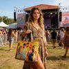 Una mujer con vestido floral y joyas sostiene un colorido bolso acolchado vintage al aire libre.