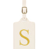 Étiquette de bagage rectangulaire en cuir beige clair avec un S brodé en or et un clip métallique argenté.