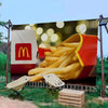 A large banner featuring a pile of french fries and the McDonald's logo against a green outdoor background.