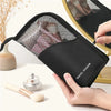 A hand holds a black foldable makeup brush storage case with a mesh top, next to a small brush.