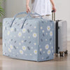 A light blue blanket storage bag is being held by a person, showing its floral pattern and size.