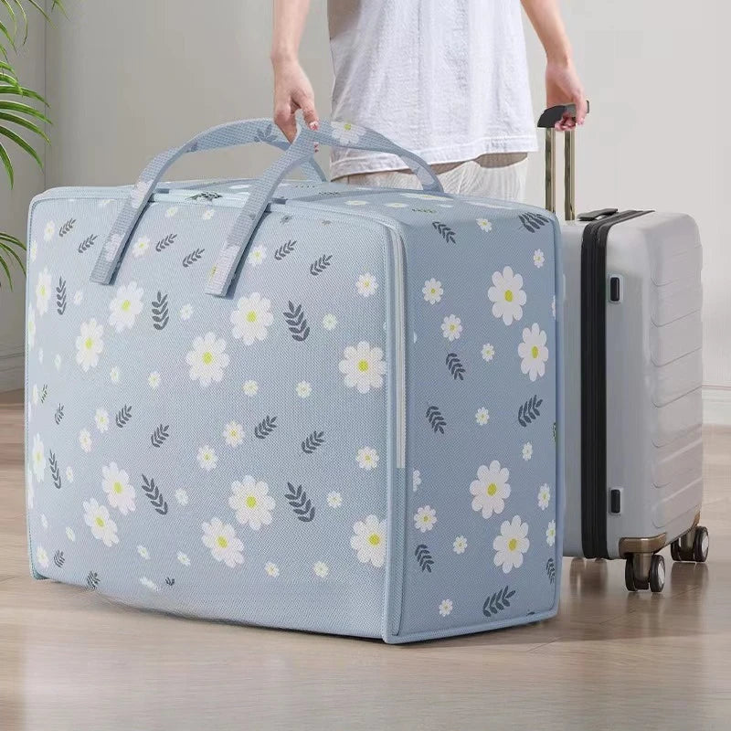 A light blue blanket storage bag is being held by a person, showing its floral pattern and size.
