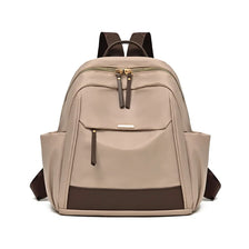 A beige lightweight nylon travel backpack with brown accents and a zippered front pocket.