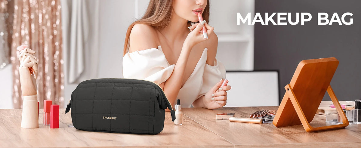 A woman holds a black padded makeup bag on a wooden table with various beauty products nearby.