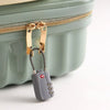 A TSA-approved 3-dial combination cable lock attached to a zipper pull on a light green plastic suitcase.
