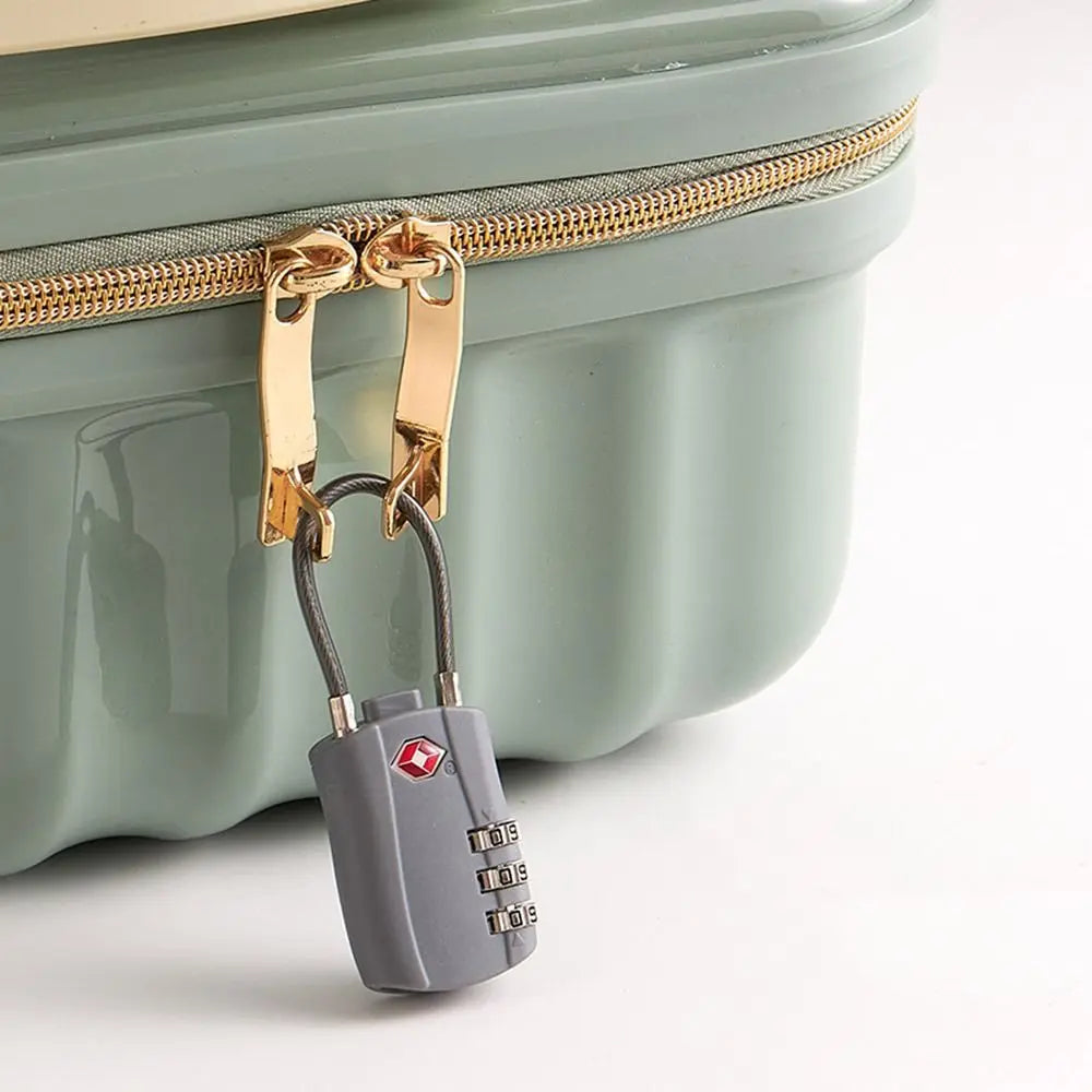 A TSA-approved 3-dial combination cable lock attached to a zipper pull on a light green plastic suitcase.