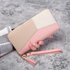 A light pink and cream patterned fashion zipper wallet is shown resting on a gray surface.