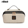 A beige travel toiletry bag with black trim and gold hardware is shown against a white background.