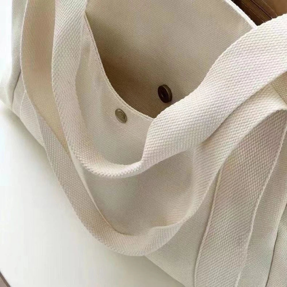 Una bolsa de lona beige doblada o colgada, destacando la textura de su tela y la abertura con cordón.