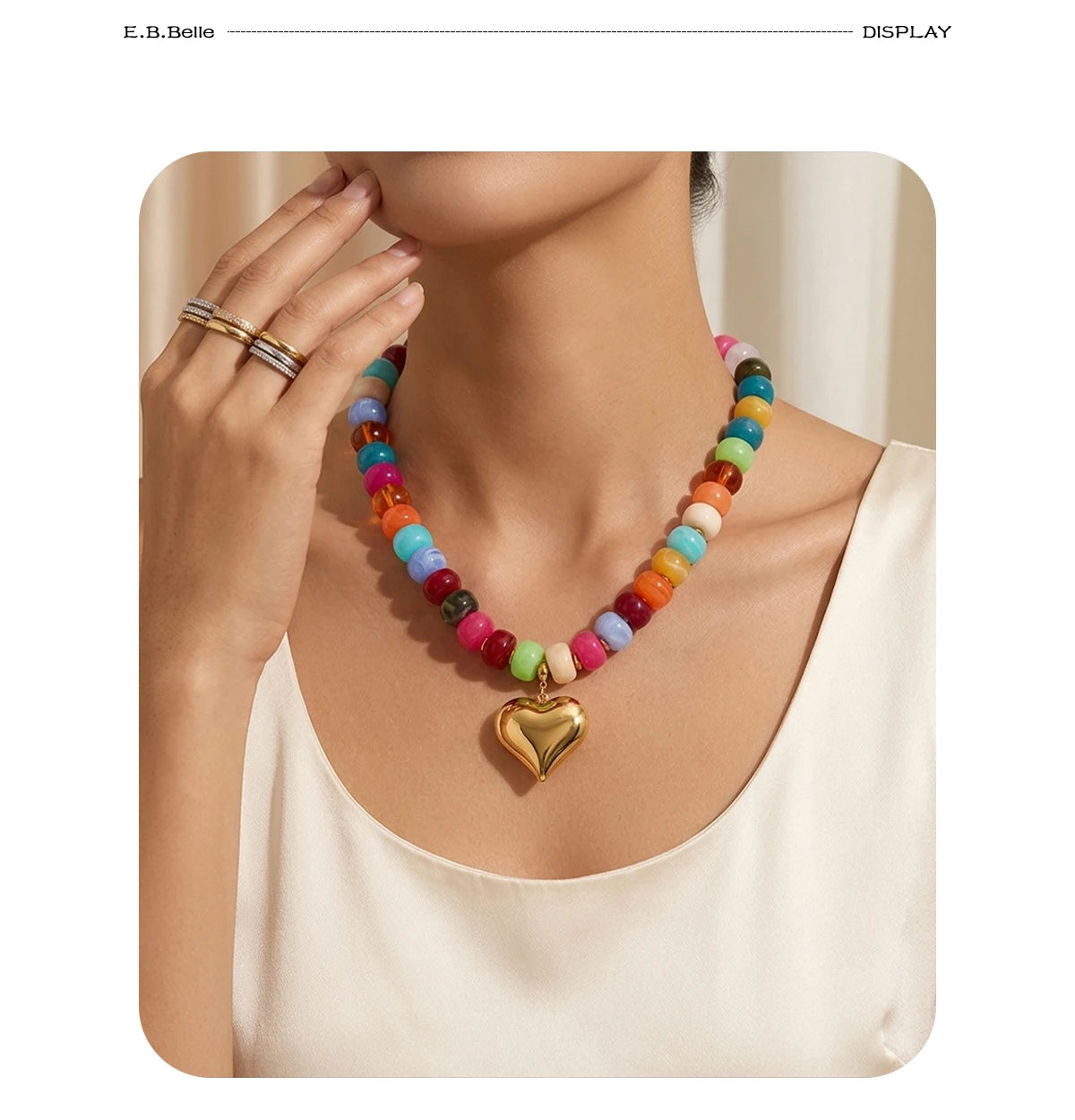 A woman is wearing a colorful bead necklace with heart-shaped charms and resin accents against a light background.