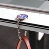 A silver hook with a purple and blue marble-like charm is attached to a white desk surface.