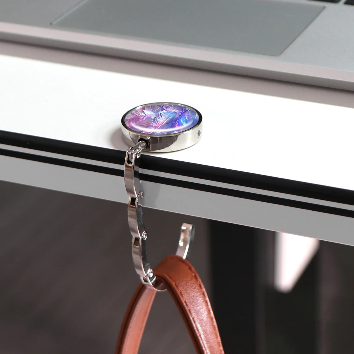 A silver hook with a purple and blue marble-like charm is attached to a white desk surface.