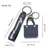 Black silicone heart beach bag keychain with a gold ring and leather strap.