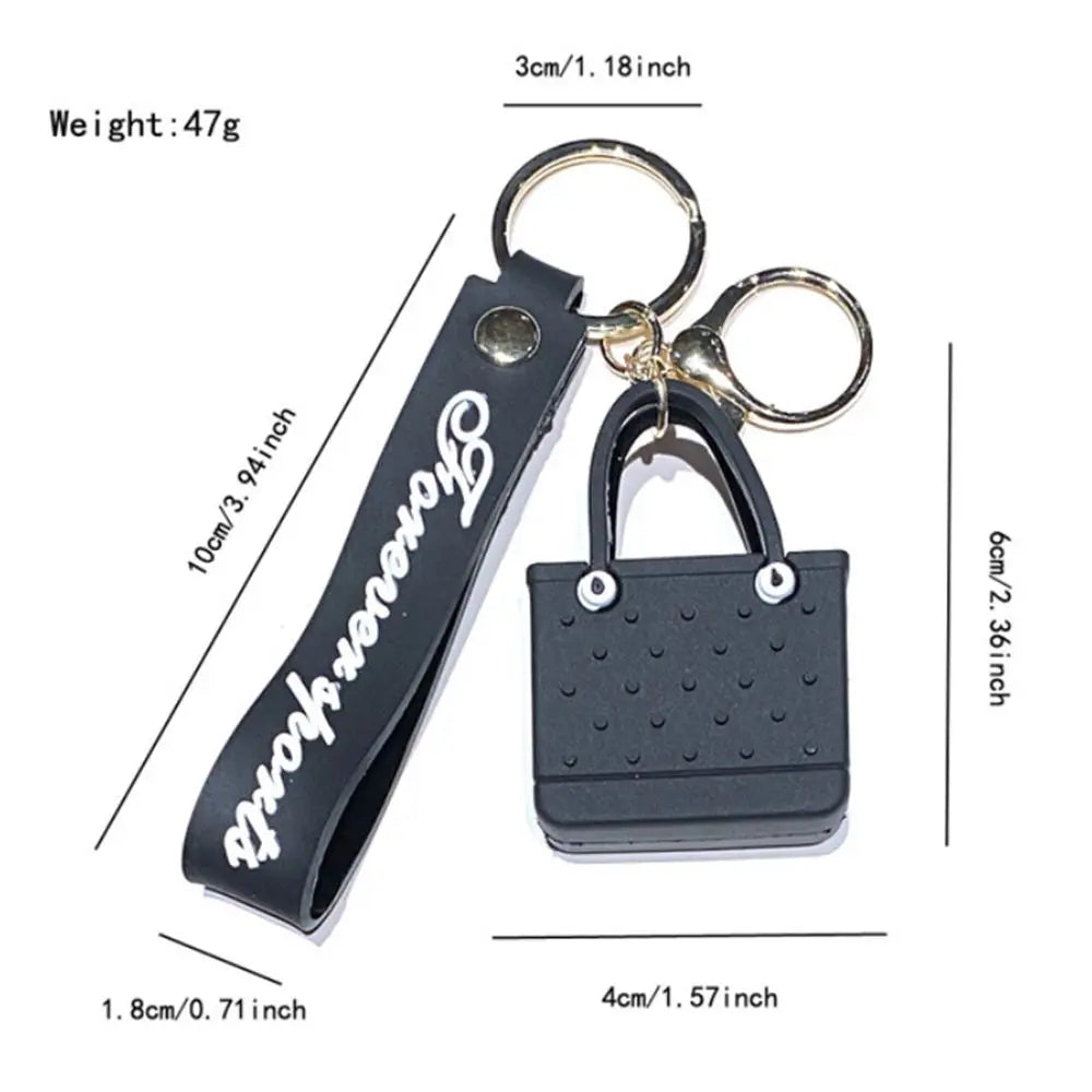 Black silicone heart beach bag keychain with a gold ring and leather strap.