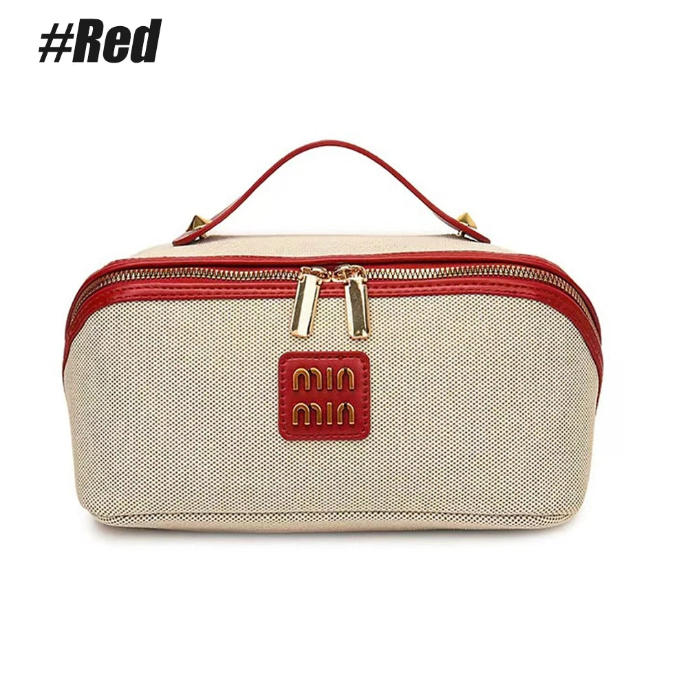 A beige and red zippered travel toiletry bag with gold hardware.