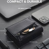 A dark gray slim aluminum pop-up card holder with a zippered compartment shown on a wooden surface.