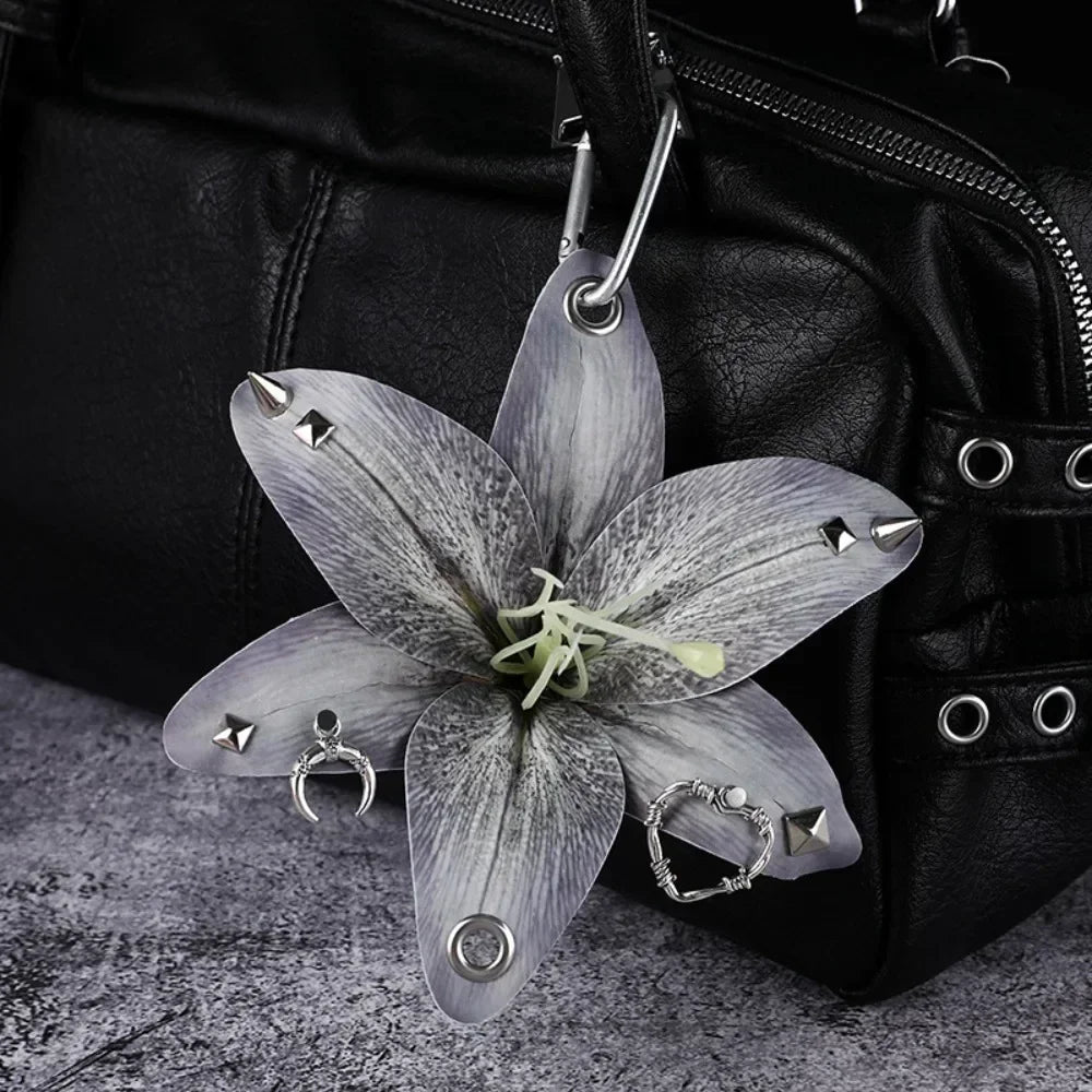 A realistic silver-gray orchid flower keychain hanging from a black leather bag.