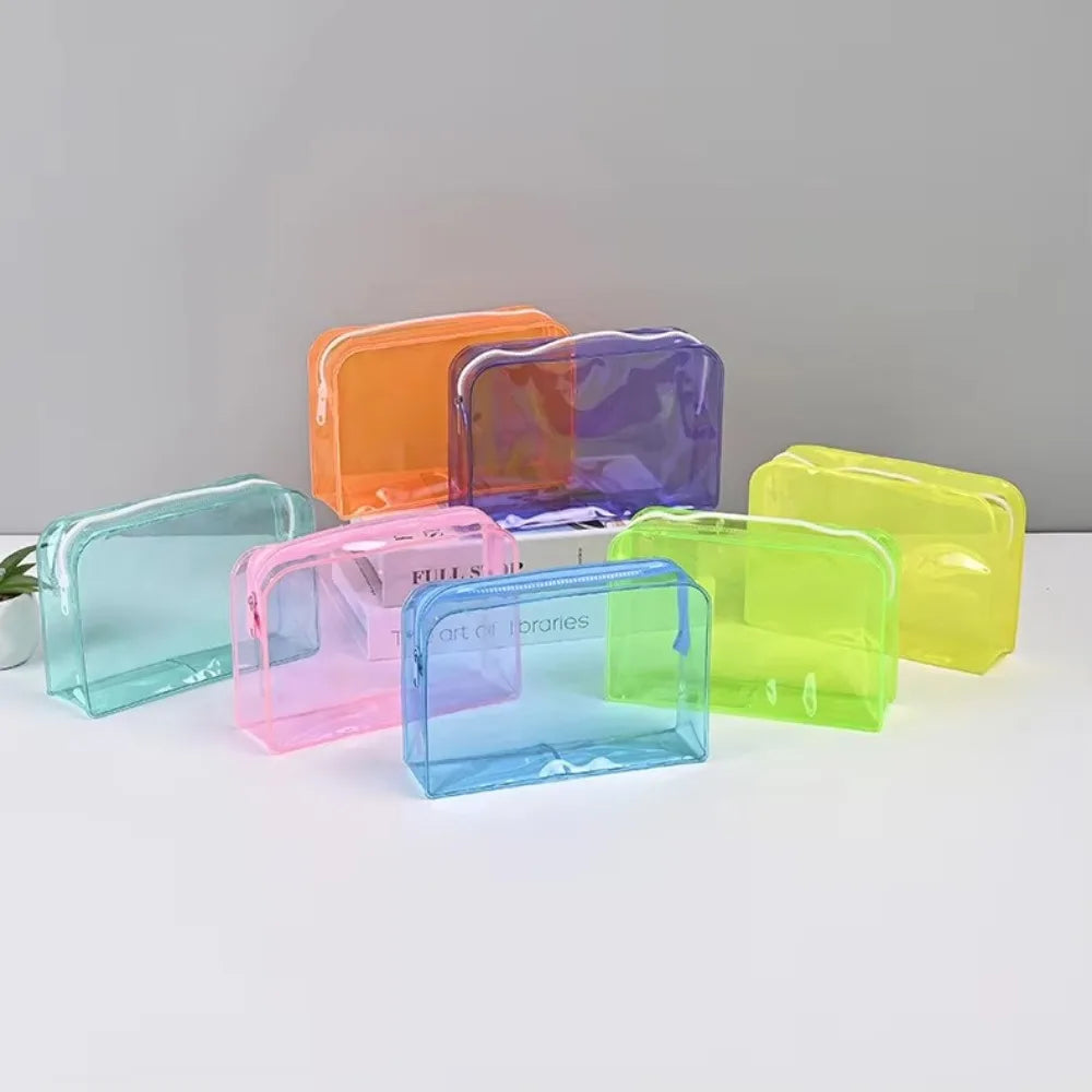 A collection of transparent PVC travel makeup bags in various colors including orange, purple, pink, blue, and lime green.
