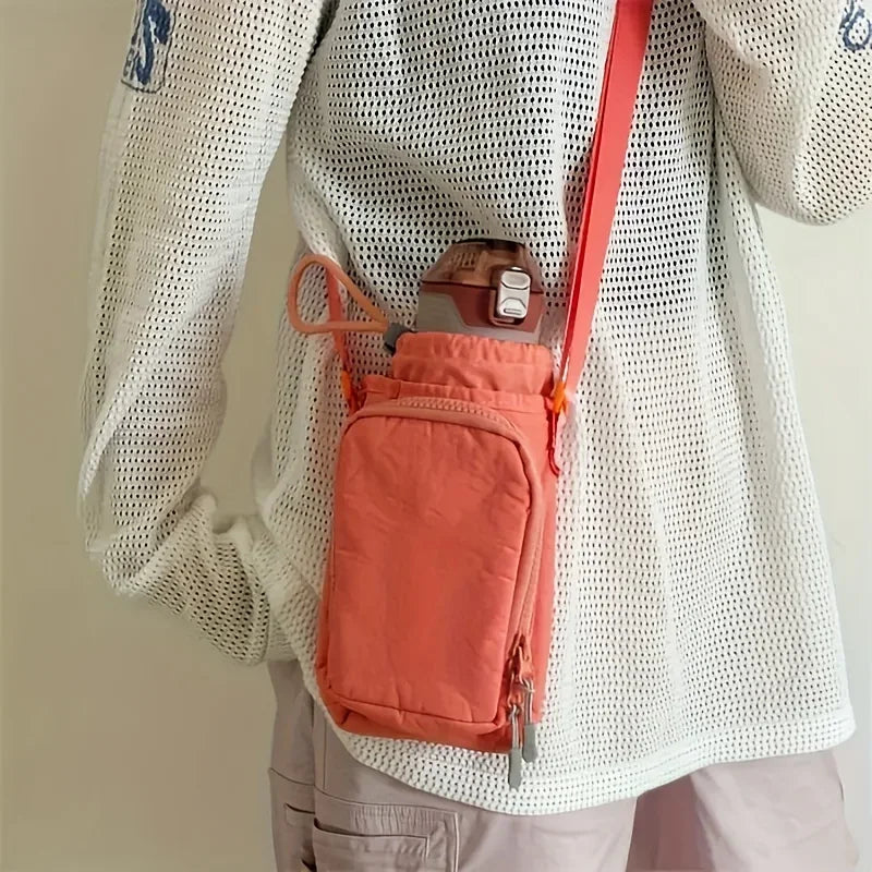 A person is wearing an orange adjustable water bottle carrier bag with a phone pocket attached to their white mesh long-sleev
