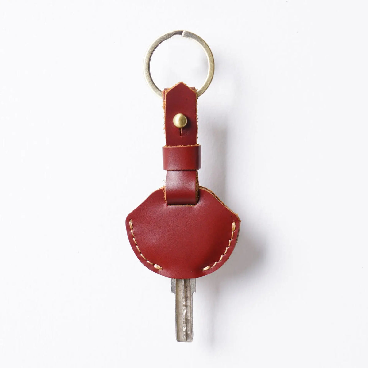 A genuine leather key fob cover with a keychain ring and a metal key attached.