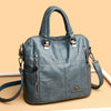 A grey leather fashionable crossbody backpack bag with silver hardware shown from the front.