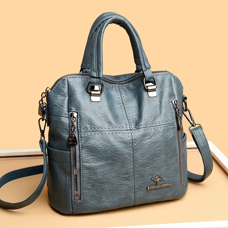 A grey leather fashionable crossbody backpack bag with silver hardware shown from the front.