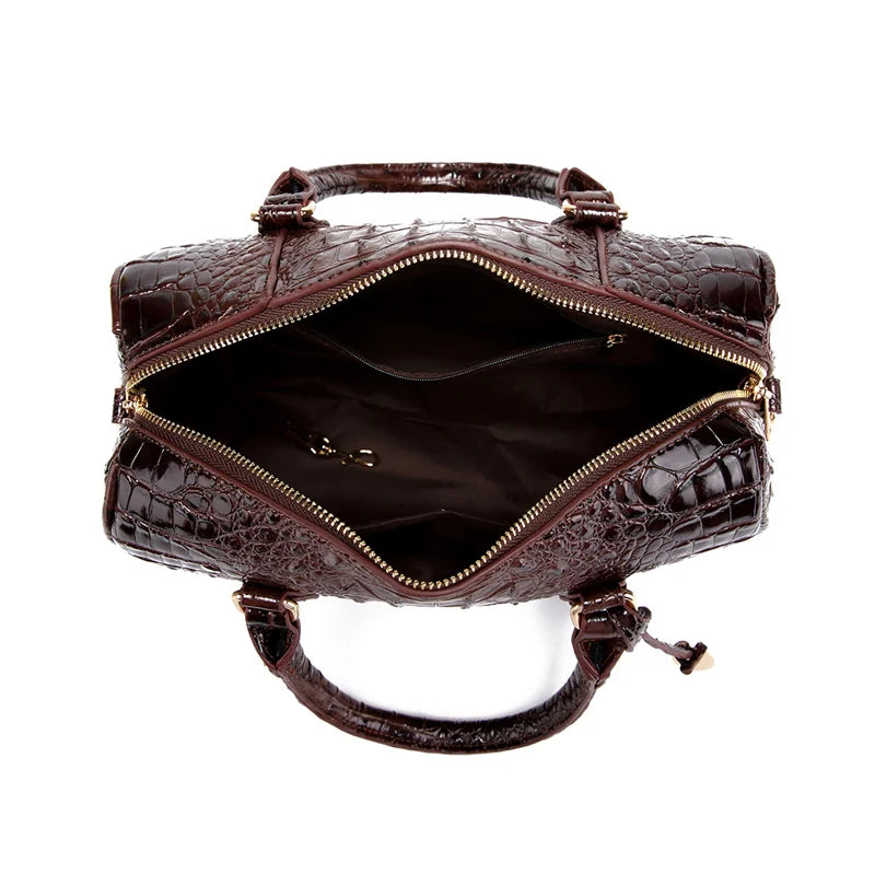 A dark brown crocodile pattern luxury handbag with gold hardware and a leather handle.