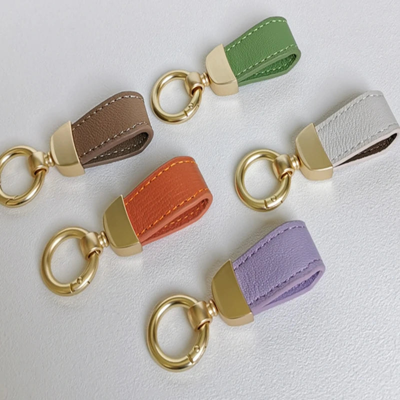 Eine Kollektion von Leder-Schafsfell-Auto-Schlüsselanhängern in verschiedenen Farben, darunter Olivgrün, Beige und Lavendel.