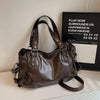 A dark brown leather commuter shoulder bag displayed on a white surface next to a sign.