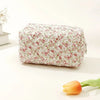 Bolsa de maquillaje con cremallera acolchada floral, fondo blanco y rosas rosadas rojas, exhibida sobre una superficie blanca