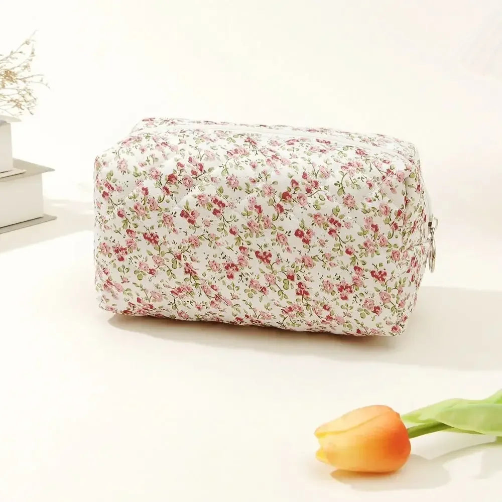 Bolsa de maquillaje con cremallera acolchada floral, fondo blanco y rosas rosadas rojas, exhibida sobre una superficie blanca