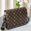 A brown men's casual crossbody bag with a patterned fabric rests on a white surface next to a pink rose.