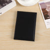 Black leather heart print passport cover travel wallet resting on a light wooden surface.