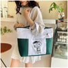 A woman holds a white and green Snoopy canvas tote bag against a light-colored background.