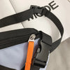 A close-up of a black nylon chest rig bag with an orange strap and black webbing.