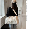 A woman wearing a black top and light pants holds a cream and beige crocodile grain PU leather travel duffle bag.