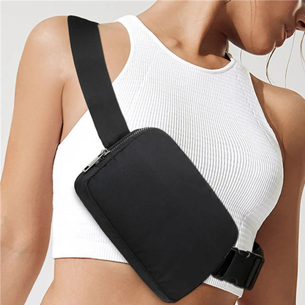 A woman wearing a white ribbed tank top with a black cross-body nylon waist bag attached.
