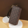 A brown patterned PU leather zippered wallet is displayed on a white stand against a dark background.