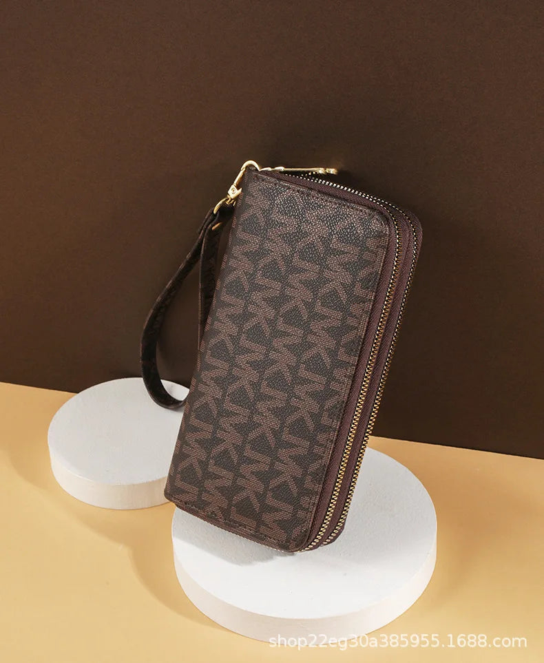 A brown patterned PU leather zippered wallet is displayed on a white stand against a dark background.